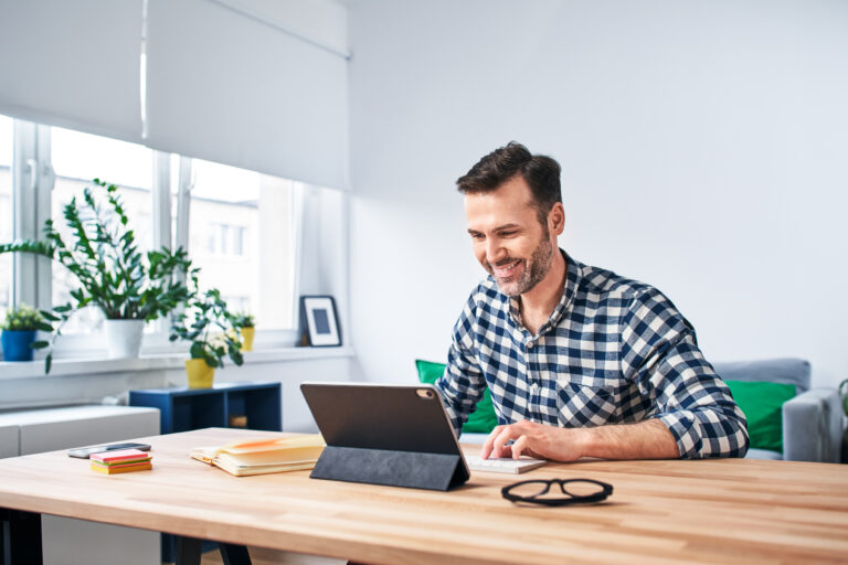 Freelancer working from home sitting at desk with digital tablet